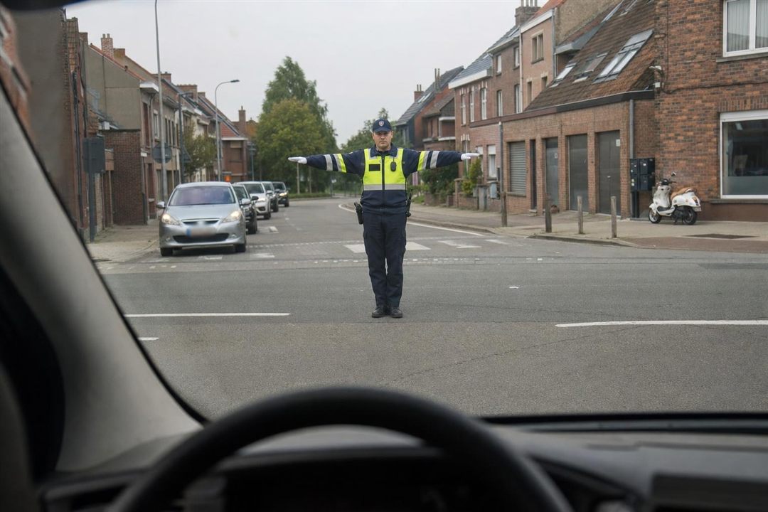Agent belge donnant l'ordre d'arrêt, bras tendus à l'horizontale, vu du pare-brise