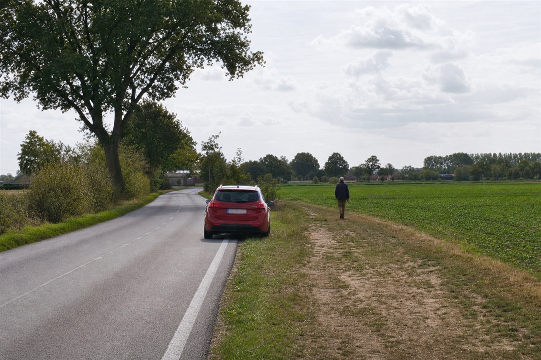 Voiture rangée sur l’accotement, un piéton marche sur la bande extérieure restée libre