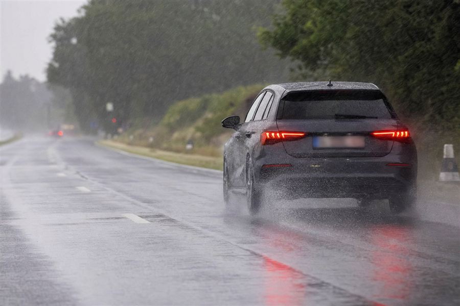 Voiture roulant sous une forte pluie d’orage, gerbes d’eau sous les pneus