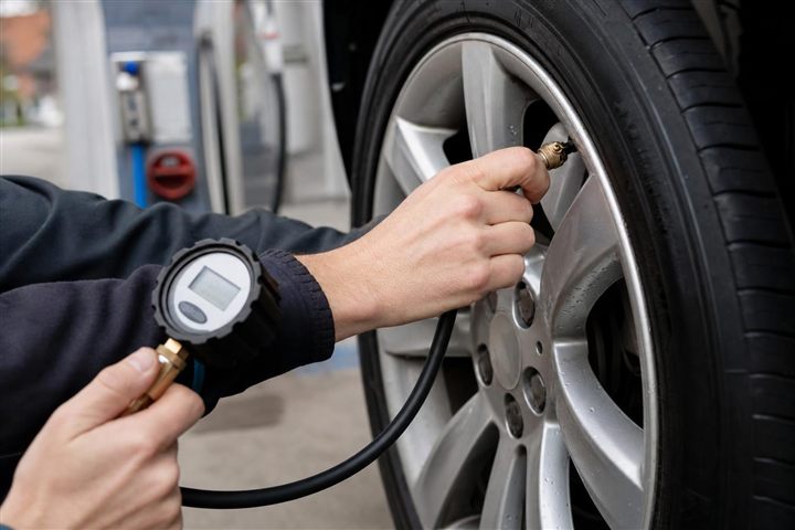 Vérification de la pression d'un pneu au manomètre en station