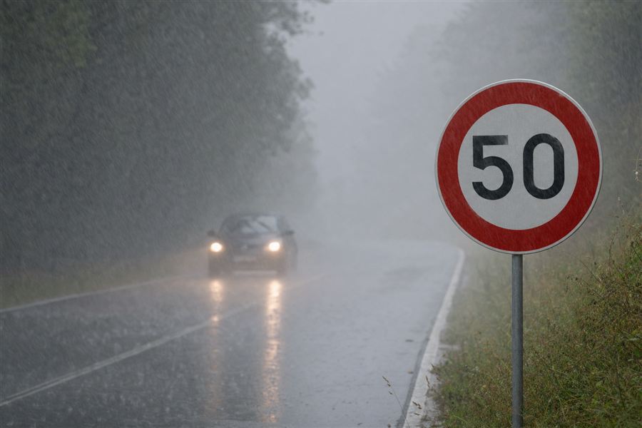 Deux voitures roulant sous une forte pluie près d’un signal de limitation à 50 km/h