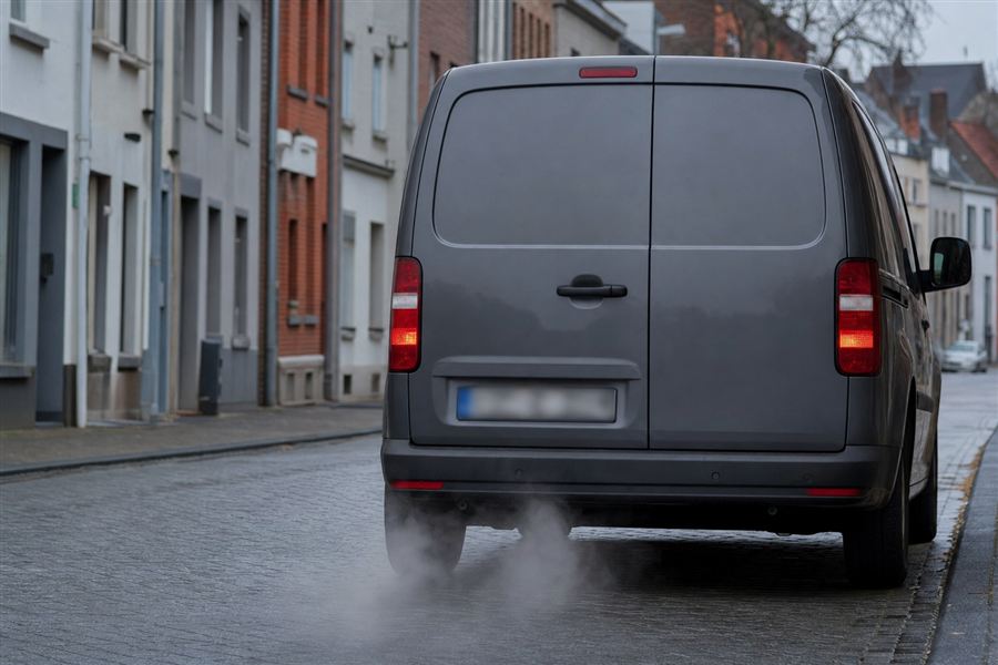 Camion à l'arrêt moteur allumé qui dégage un épais nuage de fumée en ville