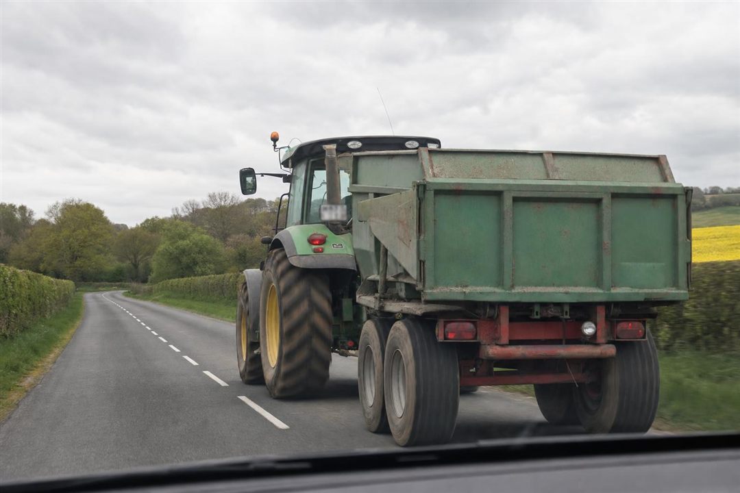 Tracteur agricole avec remorque sur une route de campagne wallonne