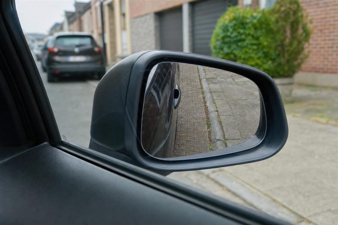 Rétroviseur droit incliné montrant la bordure du trottoir pendant le créneau