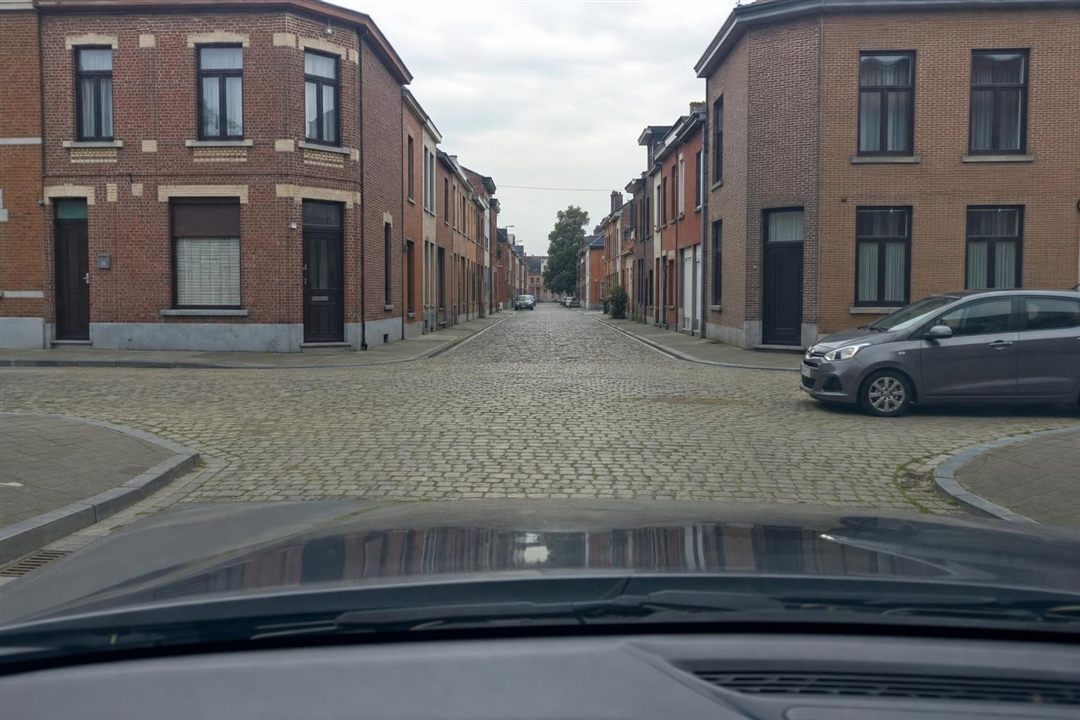 Carrefour belge sans signalisation avec une voiture arrivant de la droite