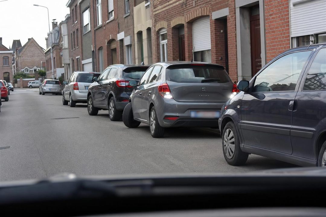 Voiture en stationnement avec feux de recul allumés et roues braquées vers la chaussée