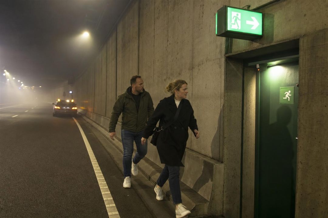 Deux occupants évacuant un tunnel vers la sortie de secours signalée en vert