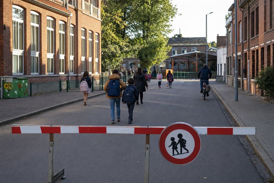 Écoliers, piétons et cyclistes circulant devant une école, dans une rue sans voitures
