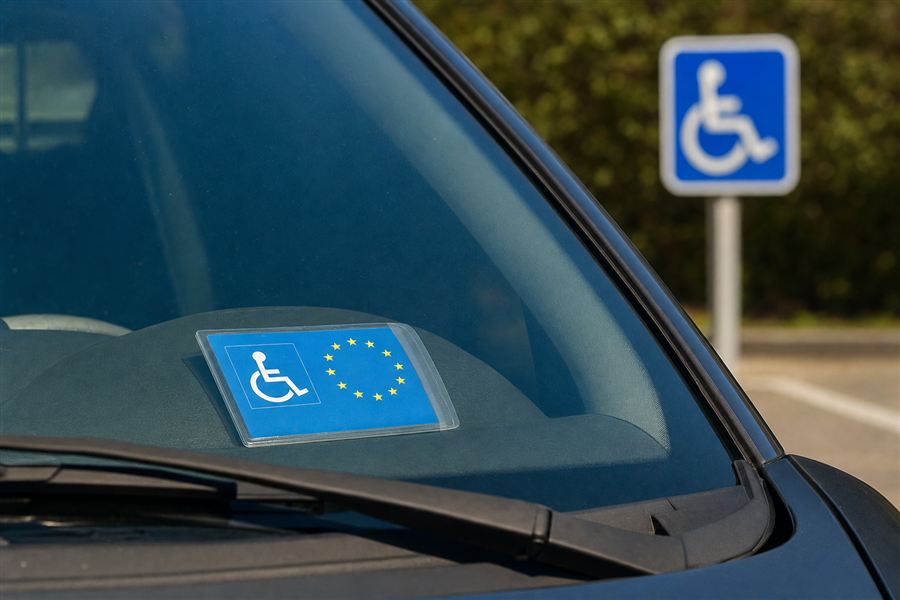 Voiture avec la carte spéciale pour personnes handicapées derrière le pare-brise, à côté du signal au symbole international